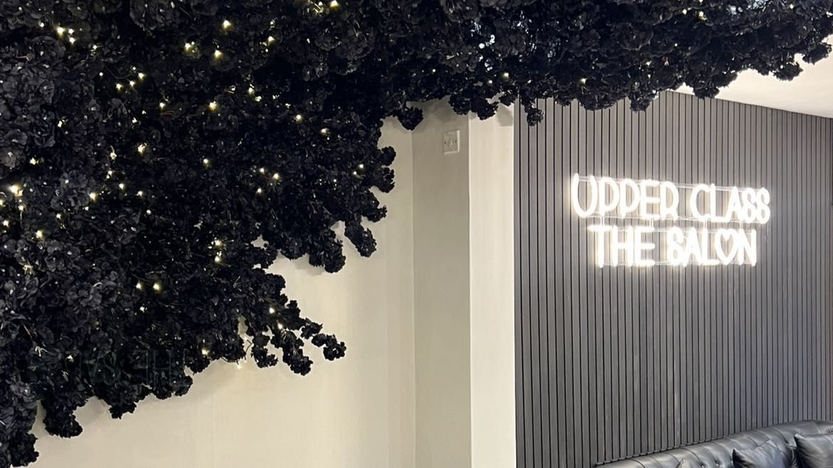 The neon Upper Class sign beside the black flower tree