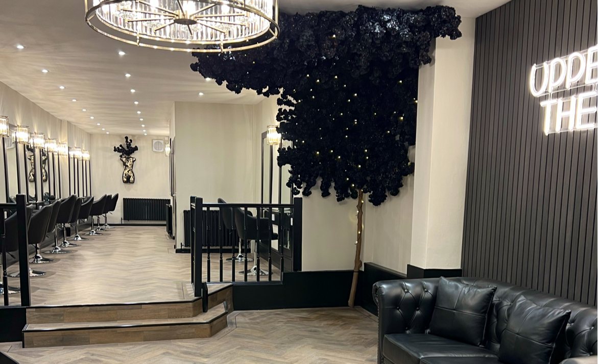 Inside Upper Class: a crystal chandelier, a black flower tree and the neon salon sign
