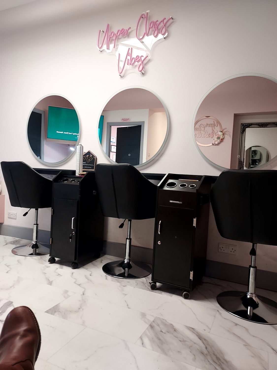 Styling stations with round mirrors and a pink neon sign