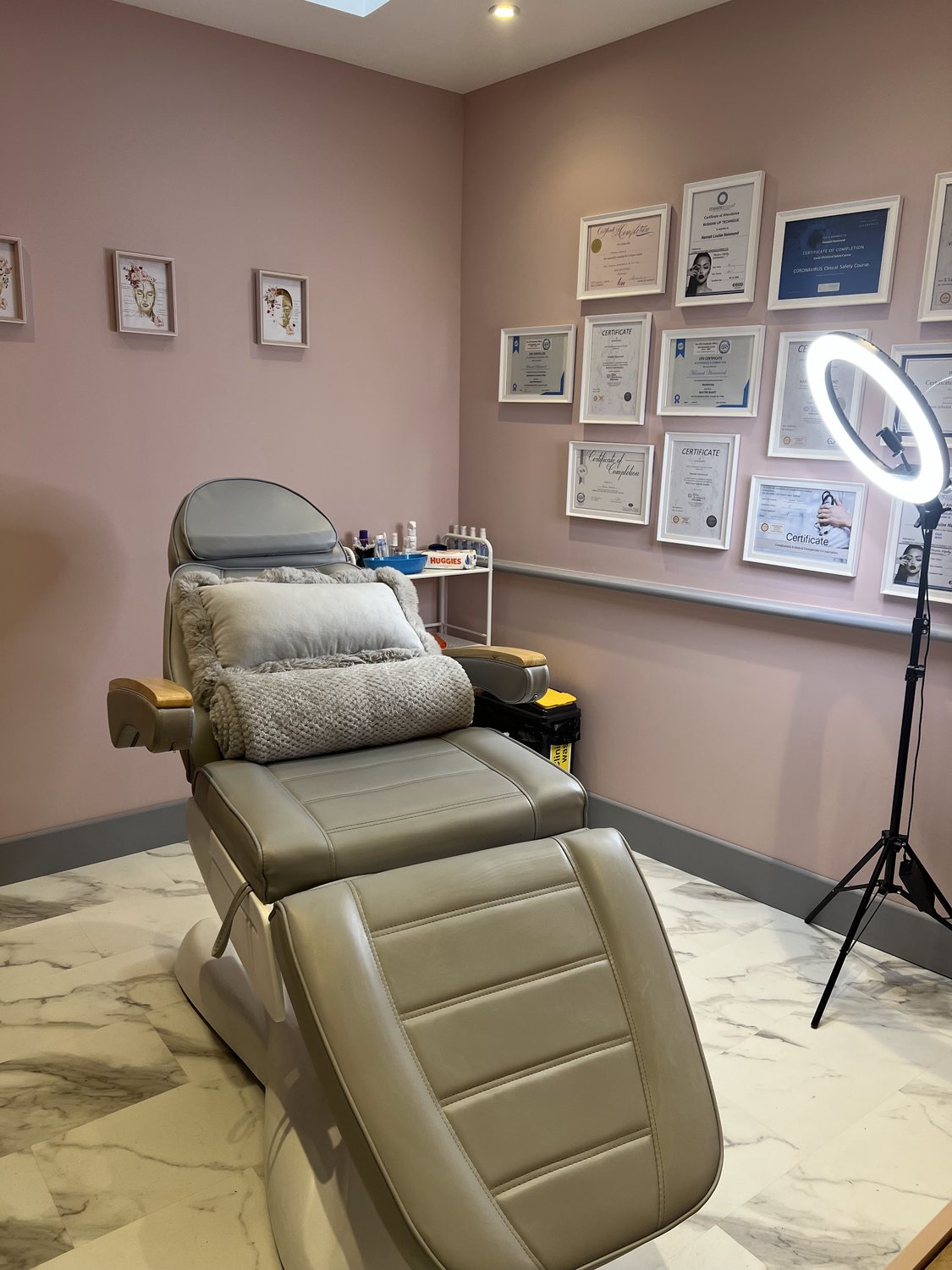 Hannah’s treatment room: a reclining treatment chair, a ring light and a wall of framed certificates